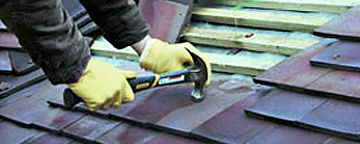 A roofer fitting tiles to a roof