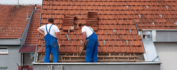 Two roofers fitting tiles